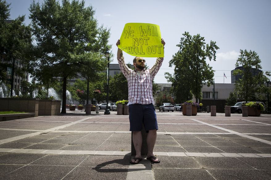 Trevor Berryhill, 29, stands with his, "We will not chill out," sign while protesting outside of City Hall while City Council members discuss retirement plan options inside the facility in Memphis, Tenn., on July 1, 2014. Berryhill said his father is a sergeant with the Memphis Police Department. (Associated Press/The Commercial Appeal)