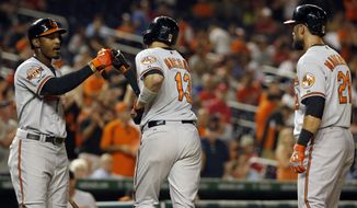 Baltimore Orioles&#39; Manny Machado (13), celebrates his two-run homer with Adam Jones left, with Nick Markakis, at right, during the 11th inning of an interleague baseball game against the Washington Nationals at Nationals Park, Monday, July 7, 2014, in Washington. The Orioles won 8-2, in 11 innings. (AP Photo/Alex Brandon)