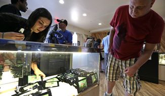 Clerk Havilah Nokes arranges packets of marijuana for sale as a customer peers in at the display at Cannabis City on the first day of legal recreational pot sales Tuesday, July 8, 2014, in Seattle. Washington on Tuesday became the second state to allow people to buy marijuana legally in the U.S. without a doctor&#39;s note as eager customers who lined up outside stores made their purchases. (AP Photo/Elaine Thompson)