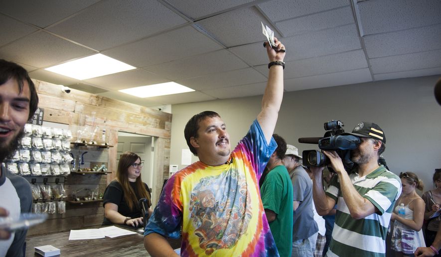 ** FILE ** Mike Boyer turns to the crowd outside, showing off the 4 grams of marijuana he bought as the first in line to legally purchase marijuana at Spokane Green Leaf, Tuesday, July 8, 2014, in Spokane, Wash.  (Associated Press)