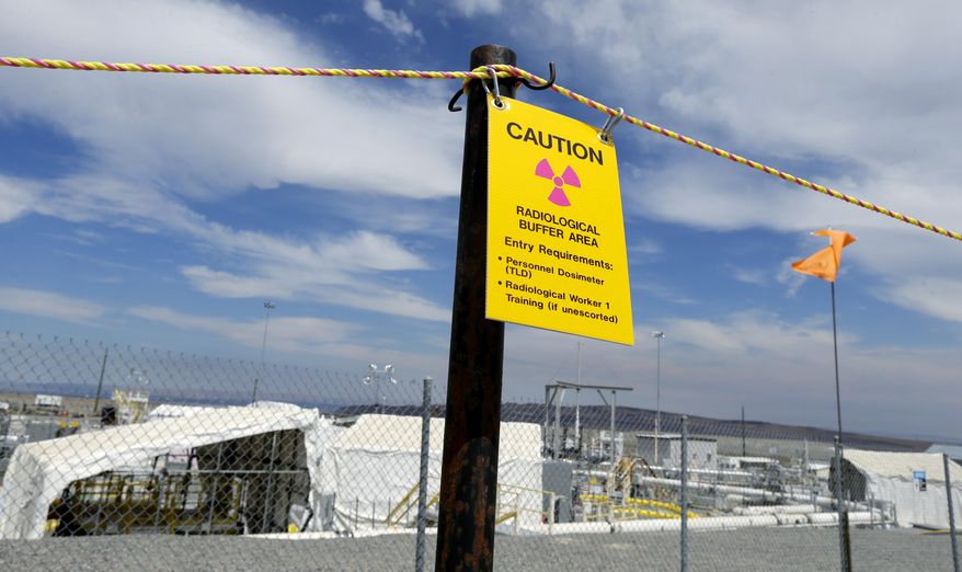A sign warns of radioactivity near a wind direction flag indicator at the "C" tank farm during a media tour of the Hanford Nuclear Reservation Wednesday, July 9, 2014 near Richland, Wash. Officials said Wednesday that 12,000 air samples taken at Hanford this year after more than three dozen workers reported being sickened by chemical vapors have failed to find a cause for the problem. (AP Photo/Ted S. Warren)