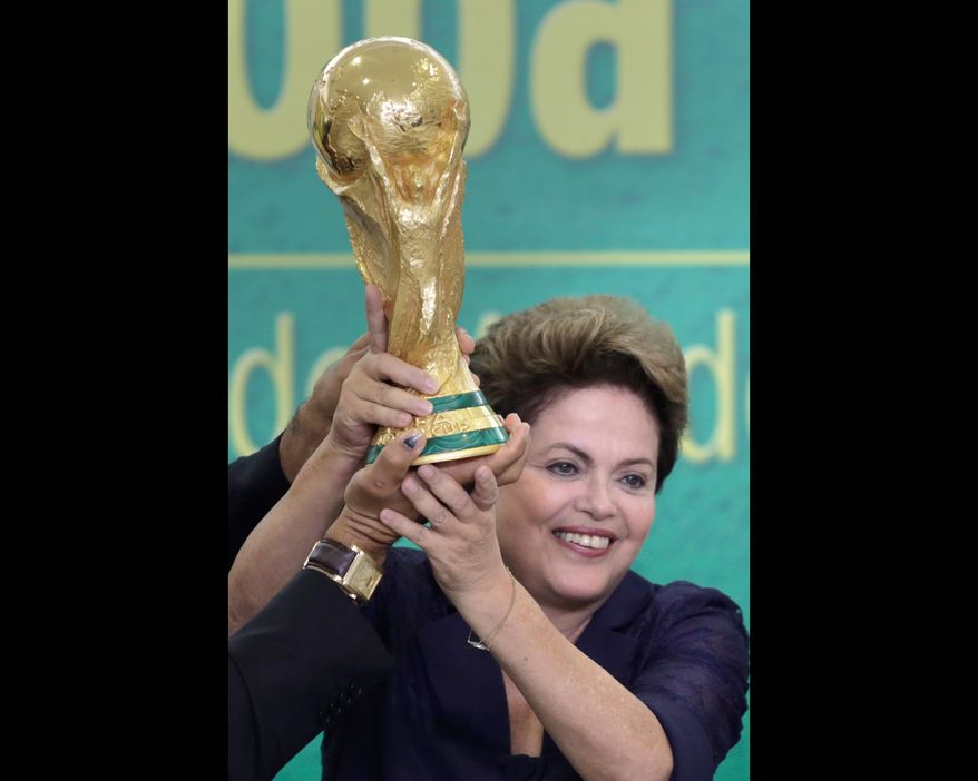 FILE - In this June 2, 2014 file photo, Brazil's President Dilma Rousseff holds up the 2014 World Cup trophy after it was officially presented to Rousseff by FIFA President Sepp Blatter, during a ceremony at the Planalto presidential palace, in Brasilia, Brazil. Rousseff met Friday, July 11, 2014 with a group of foreign journalists in Brasilia, where she hailed Brazil proved skeptics wrong who said the nation couldn't organize a successful World Cup, and said it boded well for its hosting of the 2016 Summer Olympics in Rio de Janeiro. (AP Photo/Eraldo Peres, File)