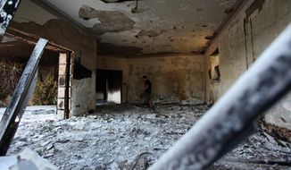 ** FILE ** This Sept. 13, 2012, file photo shows a man walking the burned shell of the U.S. Consulate, in Benghazi, Libya, after an attack that killed four Americans, including Ambassador J. Christopher Stevens. (AP photo/Mohammad Hannon, File)