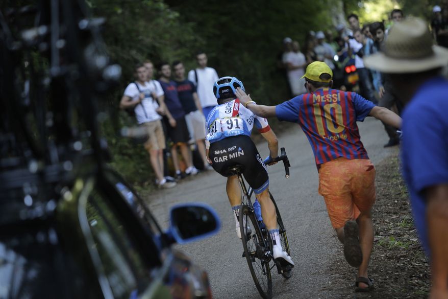 A spectators who wanted to encourage Andrew Talansky of the U.S. pats him on his aching back when riding alone distanced from the pack during the eleventh stage of the Tour de France cycling race over 187.5 kilometers (116.5 miles) with start in Besancon and finish in Oyonnax, France, Wednesday, July 16, 2014. Talansky crashed twice in the first week of the Tour. (AP Photo/Laurent Cipriani)