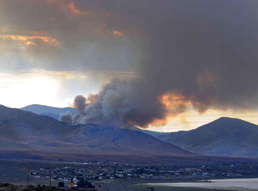 A wildfire fills the sky with smoke north and above Bordertown, Nev., Tuesday July 15, 2014. Wildfires were also burning in Idaho, Oregon and California on Wednesday. (AP Photo/The Reno Gazette-Journal, Marilyn Newton) NO SALES; NEVADA APPEAL OUT; SOUTH RENO WEEKLY OUT