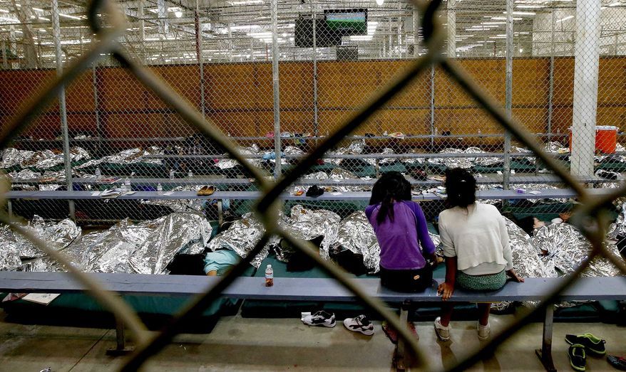 FILE - In this Wednesday, June 18, 2014, file photo, two young girls watch a World Cup soccer match on a television from their holding area where hundreds of mostly Central American immigrant children are being processed and held at the U.S. Customs and Border Protection Nogales Placement Center in Nogales, Ariz. As of Thursday, July 17, 2014, immigrant children caught crossing the Mexican border into Texas illegally and alone are no longer being sent to a massive Nogales facility. (AP Photo/Ross D. Franklin, Pool, File)