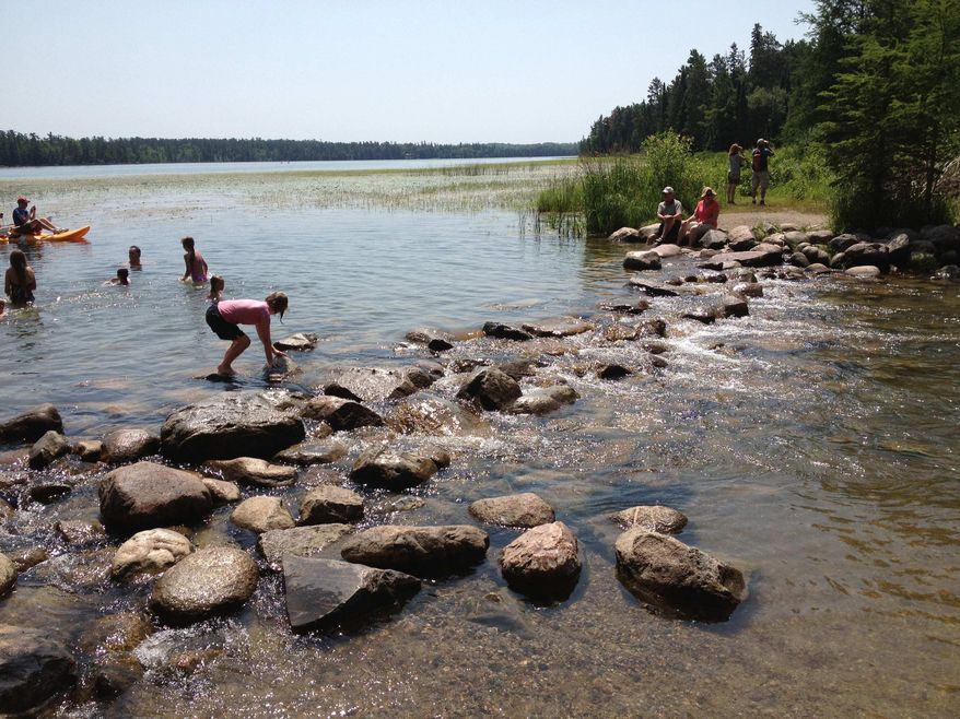 In this July, 2012 photo, crossing the headwaters of the Mississippi River at Itasca State Park near Bemidji, Minn. is nearly a rite of passage in Minnesota. Forget all that carping about Minnesota's dank and dismal early summer. The state says more people than ever are taking advantage of Minnesota's network of state parks. They credit promotional efforts paid by a special revenue stream for the uptick. (AP Photo/St. Cloud Times, Ann Wessel)