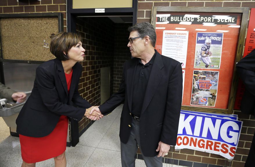 Texas Gov. Rick Perry greets Iowa Lt. Gov. Kim Reynolds, left, during a meeting with local party activists, Saturday, July 19, 2014, in Algona, Iowa. After his presidential bid crashed in 2012, Iowans now have to decide whether to give Perry another spin. (AP Photo/Charlie Neibergall)