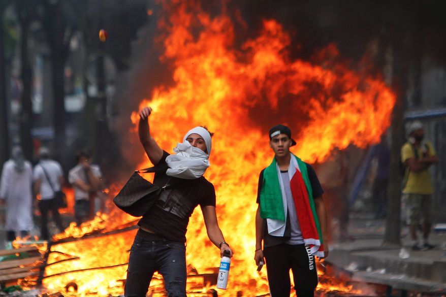 A pro-Hamas demonstrator throws a stone toward riot police, during a demonstration in Paris on July 19. (AP Photo/Thibault Camus)