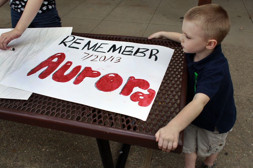 ** FILE ** In this July 19, 2013, file photo, 4-year-old Jake Richards watches as his sister Stephanie makes signs reading "Remember Aurora," during a remembrance event at which the names of people killed by gun violence in America over the previous year were read aloud, at Cherry Creek State Park in Aurora, Colo. (AP Photo/Brennan Linsley, file)