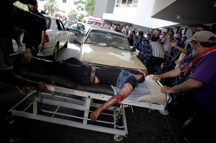 In this Saturday, July 12, 2014 photo, Palestinian medics wheel an injured man on a stretcher into the Shifa hospital after an Israeli missile strike in Gaza City. In the heart of Gaza City, as its citizen again find themselves under fire from Israeli airstrikes and artillery, the wounded and their wailing families stream into Shifa Hospital without end. (AP Photo/Khalil Hamra)