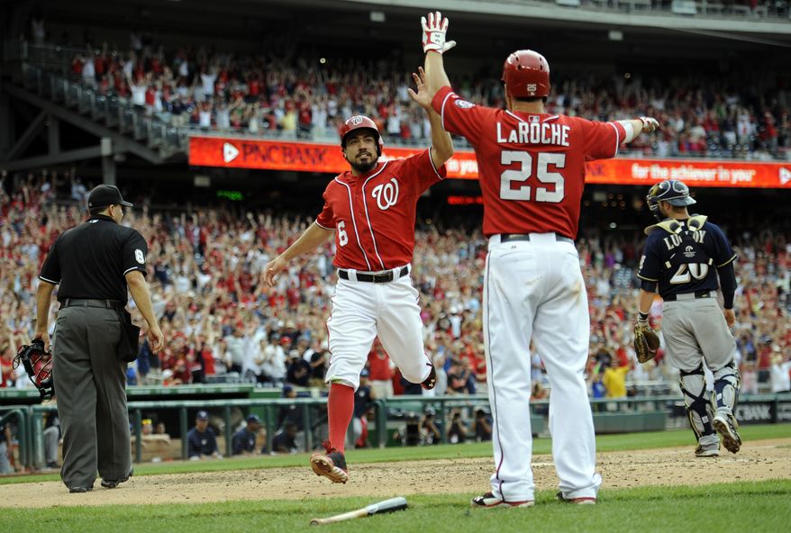 Washington Nationals' Anthony Rendon (6) celebrates after he scored the winning run with Adam LaRoche (25) on a walk off hit by Jayson Werth with during the ninth inning of a baseball game as Milwaukee Brewers catcher Jonathan Lucroy looks on at right, Sunday, July 20, 2014, in Washington. The Nationals won 5-4. (AP Photo/Nick Wass)