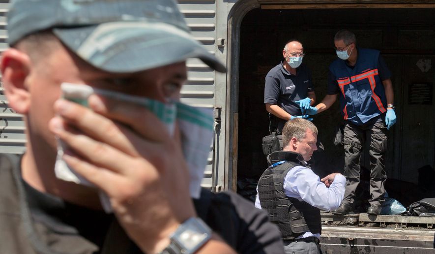 A difficult duty: The stench of death was nearly overwhelming Monday as Alexander Hug (center right), deputy head of the Organization for Security and Cooperation in Europe, led a forensics investigation team near the crash site of Malaysia Airlines Flight 17 in eastern Ukraine. (Associated Press)
