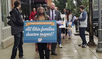 **FILE** Gay marriage supporters march to the office of Ohio Attorney General Mike DeWine in Columbus, Ohio, on May 15, 2014, to deliver petitions urging him to drop his appeal of a federal judge&#39;s order on same-sex marriage. The group, Why Marriage Matters Ohio, delivered over 6,000 signatures to DeWine&#39;s office, demanding he stop the appeal. (Associated Press)