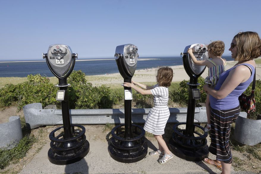 In this July 2, 2014, photo, Molly Saint-James, of Baltimore, right, helps her daughters Ellie McDonald, left, 6, and Poppy McDonald, 3, use telescopic viewers overlooking a beach while on vacation in Chatham, Mass. (AP Photo/Steven Senne)