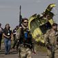 A pro-Russian rebel holds a gun passing by plane wreckage as members of the OSCE mission to Ukraine arrive for a media briefing at the crash site of Malaysia Airlines Flight 17, near the village of Hrabove, eastern Ukraine, Tuesday, July 22, 2014. (AP Photo/Vadim Ghirda) ** FIL E**
