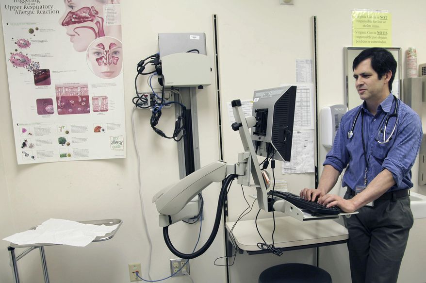 ** FILE ** In this July 11, 2014, photo, primary care doctor John Guerreiro checks on the records of a patient at a clinic run by the Virginia Garcia Memorial Health Center in Beaverton, Ore. The center comprised of nine clinics in northwestern Oregon, serveing 36,000 patients in Washington and Yamhill has been overwhelmed under the Affordable Health Care Act's Medicaid expansion. It has closed to new enrollees and is working through a backlog to assign thousands of patients to a doctor. (AP Photo/Gosia Wozniacka)