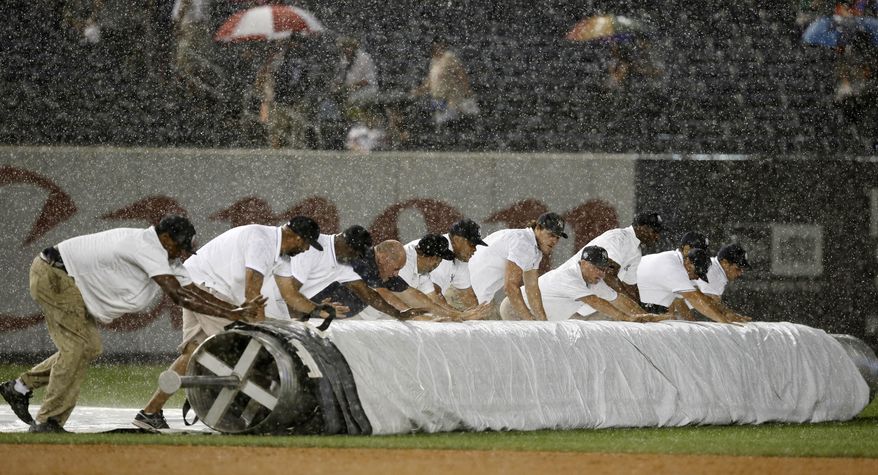 Grounds crew members unroll the tarp during a sudden rainstorm in the fifth inning of a baseball game between the Texas Rangers and the New York Yankees at Yankee Stadium in New York, Wednesday, July 23, 2014. (AP Photo)