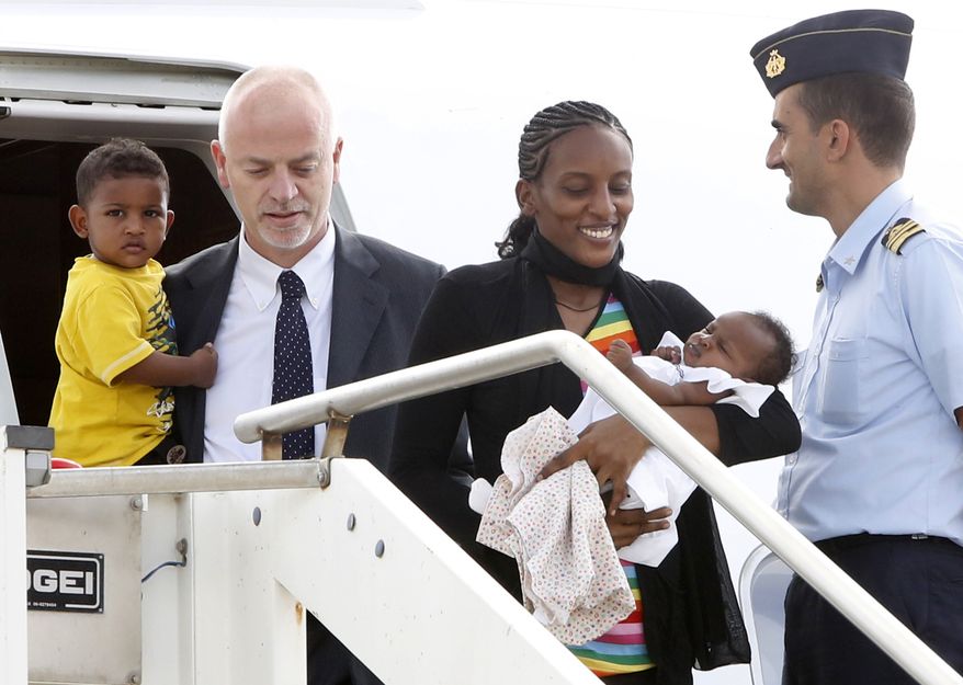 Meriam Ibrahim, from Sudan, disembarks with her children Maya, in her arms, and Martin, accompanied by Italian deputy Foreign Minister Lapo Pistelli, after landing from Khartoum, at Ciampino's military airport, on the outskirts of Rome, Thursday, July 24, 2014. The Sudanese woman who was sentenced to death in Sudan for refusing to recant her Christian faith has arrived in Italy along with her family, including an infant born in prison. An Italian diplomat who accompanied the family from Sudan said Italy leveraged its historic ties within the Horn of Africa region to help win her release. (AP Photo/Riccardo De Luca)