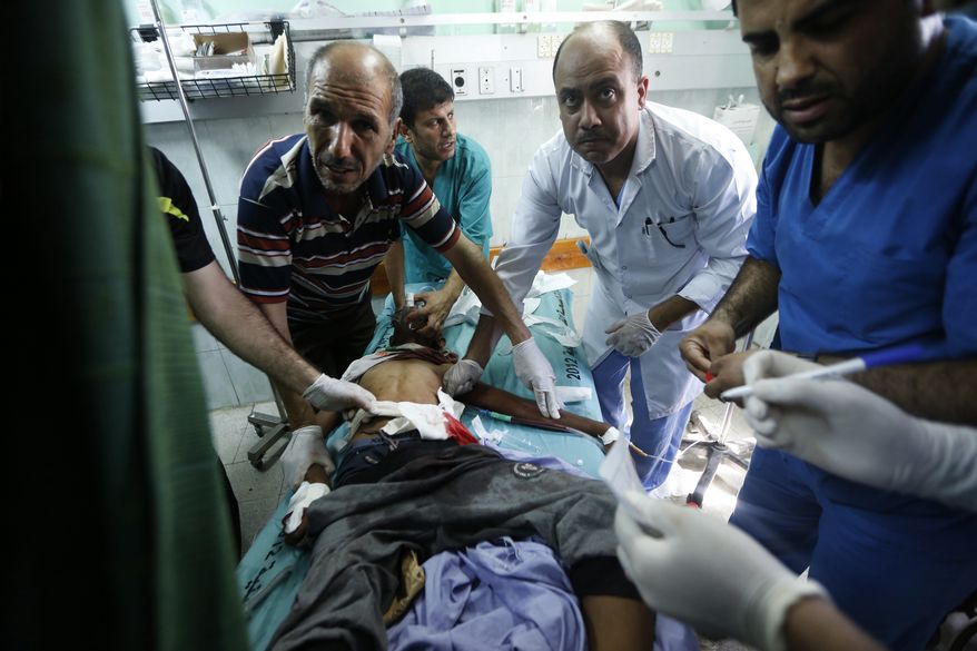 Palestinian medics treat a child wounded in an Israeli strike on a compound housing a U.N. school in Beit Hanoun, in the northern Gaza Strip, at the emergency room of the Kamal Adwan hospital in Beit Lahiya, Thursday, July 24, 2014. Israeli tank shells hit the compound, killing more than a dozen people and wounding dozens more who were seeking shelter from fierce clashes on the streets outside. (AP Photo/Lefteris Pitarakis)