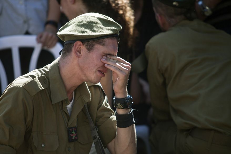 An Israeli soldier mourns over the grave of reserve Master Sgt. Yair Ashkenazy, 36, during his funeral at the military cemetery in Rehovot, Israel, Friday, July 25, 2014. Ashkenazy was killed early Friday during operations in the northern Gaza Strip, the Israel Defense Forces reported. (AP Photo/Dan Balilty)