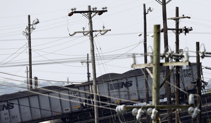 In this May 22, 2014, photo, train cars containing coal are seen past power lines as they are pushed up an incline before being unloaded at Norfolk Southern&#39;s Lamberts Point coal terminal in Norfolk, Va. As the Obama administration weans the U.S. off dirty fuels blamed for global warming, energy companies have been sending more of America&#39;s unwanted energy leftovers to other parts of the world where they could create even more pollution. (AP Photo/Patrick Semansky)