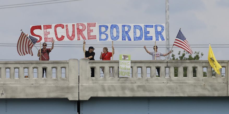 FILE - This July 18, 2014, file photo shows demonstrators with signs on an overpass in Indianapolis, to protest against people who immigrate illegally. Even as they grapple with an immigration crisis at the border, White House officials are making plans to act before November’s mid-term elections to grant work permits to potentially millions of immigrants in this country illegally, allowing them to stay in the United States without threat of deportation, according to advocates and lawmakers in touch with the administration. (AP Photo/Darron Cummings, File)
