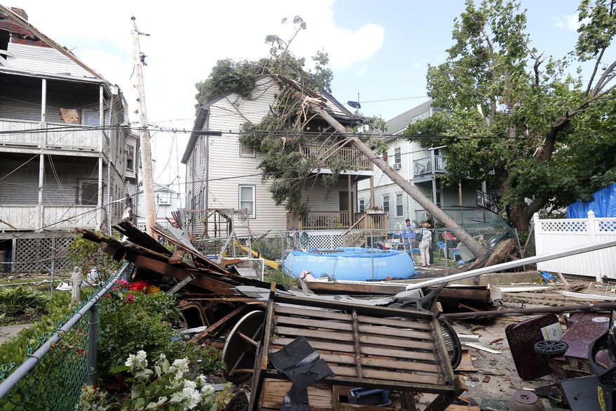 People observe the damage in the back of several houses in Revere, Mass. Monday, July 28, 2014, after a tornado touched down. Revere Deputy Fire Chief Mike Viviano says the fire department in that coastal city has received dozens of calls reporting partial building and roof collapses, and downed trees and power lines. Viviano says there are no immediate reports of deaths or serious injuries. (AP Photo/Elise Amendola)