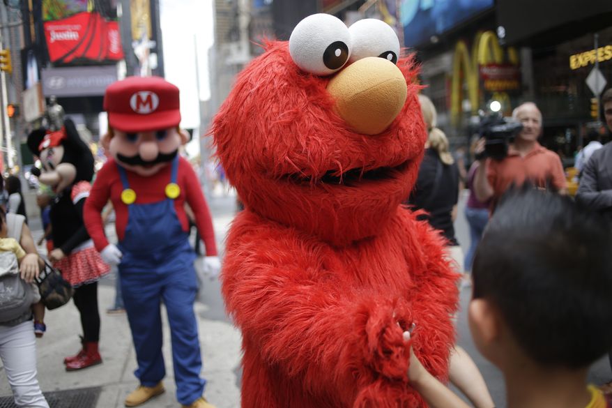 ** FILE ** A person dressed as Elmo shakes hands with a pedestrian in Times Square on Monday, July 28, 2014, in New York. New York City Mayor Bill de Blasio said Monday that he believes the people wearing character costumes in Times Square should be licensed and regulated. (AP Photo/Seth Wenig)