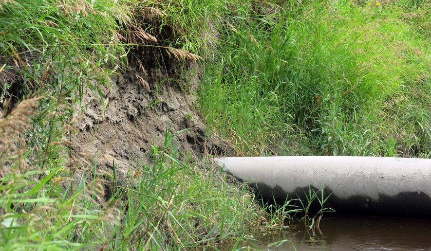 In a July 24, 2014 photo, an Enbridge crude oil pipeline is exposed by erosion where it crosses the Tamarac River in northwestern Minnesota. Three of the seven lines that cross the river are exposed. Floodwater has eroded soil that once buried the pipelines several feet below ground. (AP Photo/MPR News, Dan Gunderson)