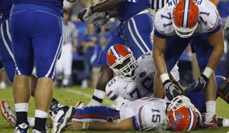 FILE - In this Sept. 26, 2009, file photo, Florida Matt Patchan (71) and Marcus Gilbert (76) look on as Florida quarterback Tim Tebow lies on the turf after being sacked during an NCAA college football game against Kentucky in Lexington, Ky. Tebow received a concussion on the play that put him in the hospital for a night. A federal judge in Chicago rejected a proposed $75 million class-action head injury settlement with the NCAA on Wednesday, portraying the deal as too unwieldy and potentially underfunded and urging both sides to go back to the drawing board. (AP Photo/Ed Reinke, File) **FILE**