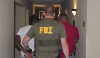 ** FILE ** In this June 2014 image from video provided by the FBI, authorities raid a hotel in Jackson, Mississippi.  When FBI agents and police officers fanned out across the country last month in a weeklong effort to rescue child sex trafficking victims, they pulled kids as young as 11 from dingy motel rooms, truck stops and homes. (AP Photo/FBI)