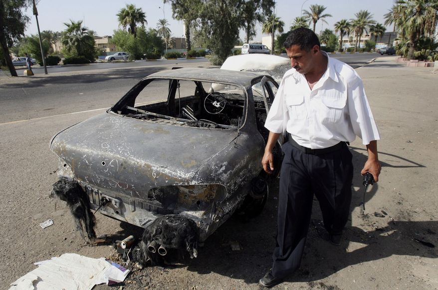 ** FILE ** An Iraqi traffic policeman inspects a car destroyed in al-Nisoor Square in Baghdad, Iraq, Sept. 25, 2007. (AP Photo/Khalid Mohammed, File)