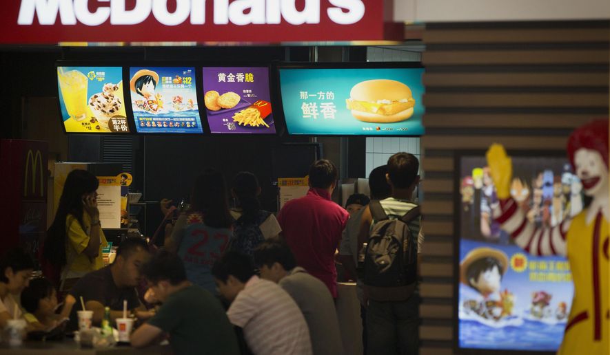 People dine at a McDonald&#x27;s restaurant as a display board, top right, shows Filet-O-Fish burger available in Beijing, China Thursday, July 31, 2014. Global fast food chains are rushing to expand in China but even experienced operators face costly pitfalls in a fast-changing food supply industry plagued by repeated safety scandals. (AP Photo/Andy Wong)