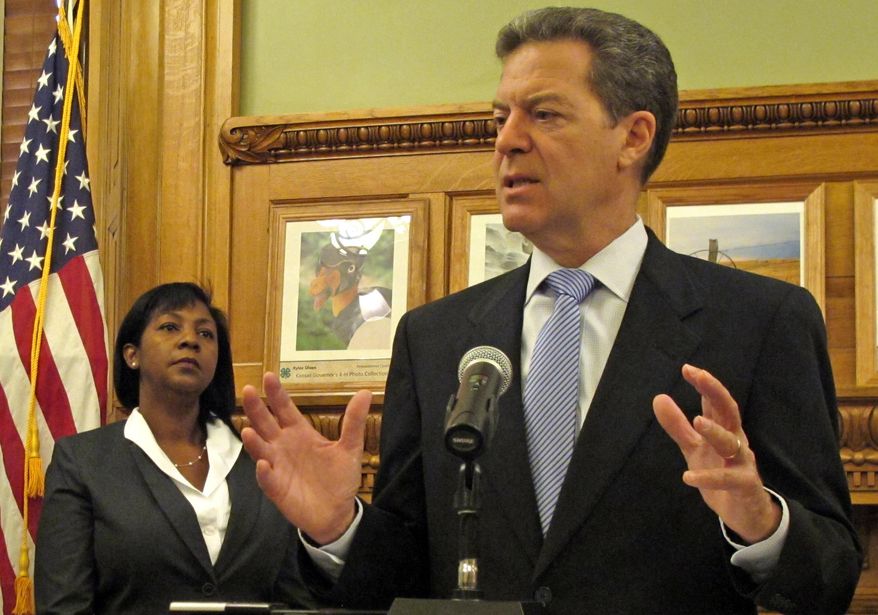 Kansas Gov. Sam Brownback discusses his three new appointments to the state Board of Regents, Friday, Aug. 1, 2014, at the Statehouse in Topeka, Kan. To his left is one of the new board members, Zoe Forrester Newton, a Sedan attorney. (AP Photo/John Hanna)