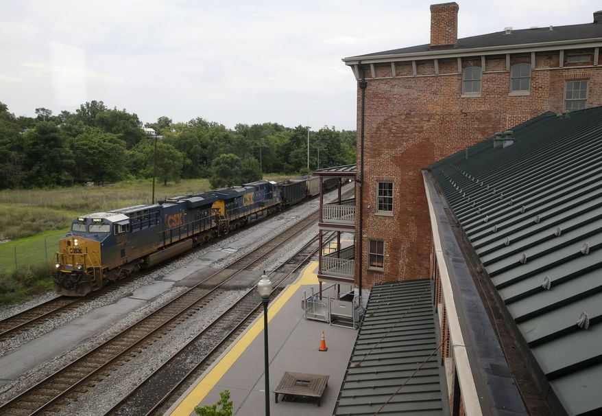 In this July 18, 2014 picture, a CSX freight train pulling empty hopper cars rolls past Caperton Transportation Center in Martinsburg, W.Va. The station serves commuters who make their way to and from Washington, D.C. Hours away from the political establishment in the capital city of Charleston, West Virginia’s eastern panhandle is growing and generating political muscle in a shriveling state. It's a fast-growing bedroom community for Washington, D.C., and it's helping shape a shift to the right with many stronghold conservative counties. (AP Photo/Patrick Semansky)