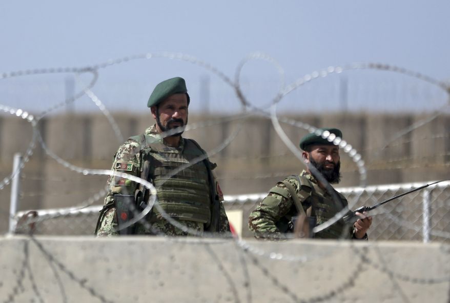 Afghanistan National Army soldiers stand guard at a gate of Camp Qargha, west of Kabul, Afghanistan, Tuesday, Aug. 5, 2014. A man dressed in an Afghan army uniform opened fire Tuesday on foreign troops at a military base, causing casualties, an Afghan military spokesman said. In a statement NATO said it was investigating an "incident" involving both Afghan and international troops at Camp Qargha which trains officers for the country's army. (AP Photo/Massoud Hossaini)