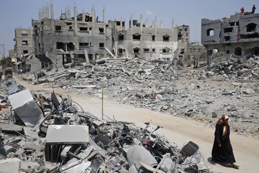 A Palestinian walks by the rubble of houses, destroyed by Israeli strikes in the town of Beit Hanoun, northern Gaza Strip, Tuesday, Aug. 5, 2014. Israel and Hamas began observing a temporary cease-fire on Tuesday that sets the stage for talks in Egypt on a broader deal on the Gaza Strip, including a sustainable truce and the rebuilding of the battered, blockaded coastal territory.(AP Photo/Lefteris Pitarakis)