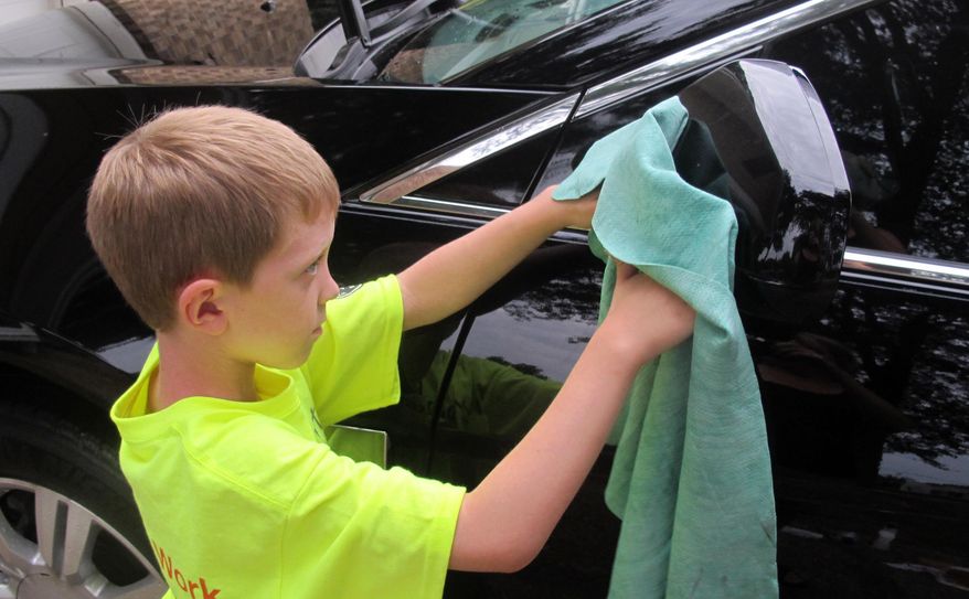 In this July 18, 2014 photo, Sterling Murset washes a car at the home of Todd Blanchieri in Pensacola, Fla. The Murset family is touring the country doing chores for families in need. (AP Photo/Melissa Nelson-Gabriel)