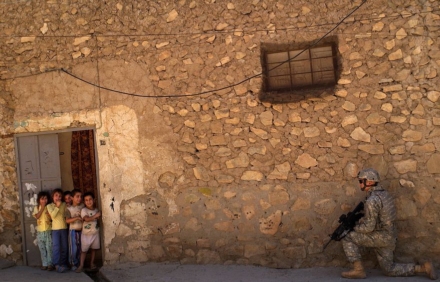Children look on as Sgt. David Ristau, 172nd Stryker Brigade Combat Team, provides security during a patrol in Sinjar's market district in 2006. (U.S. Air Force via Associated Press)