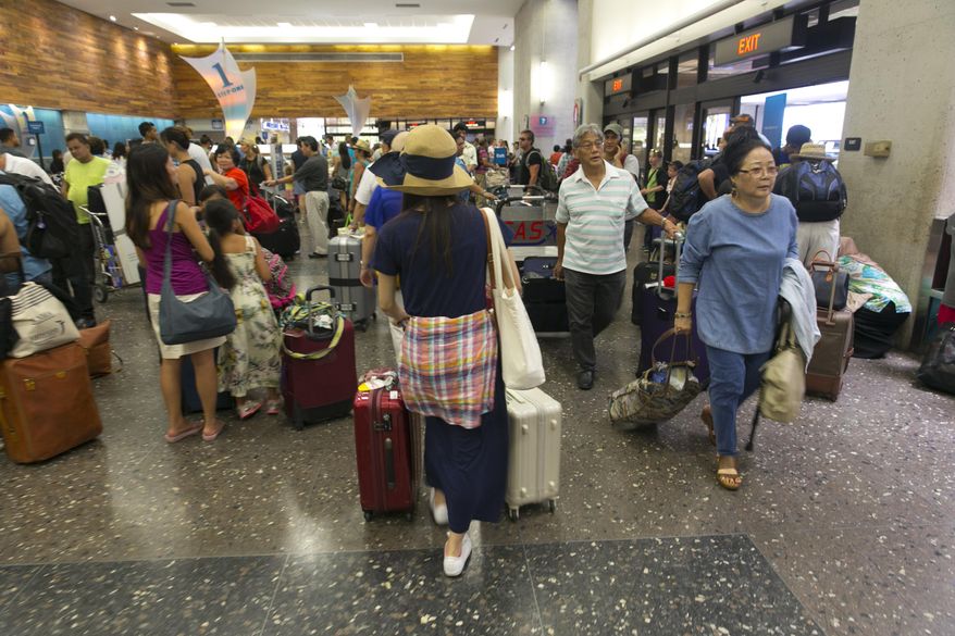 Crowds line up inside the departures terminal at the Honolulu International Airport in Honolulu on Thursday, Aug. 7, 2014. With Iselle, Hawaii is expected to take its first direct hurricane hit in 22 years. Tracking close behind it is Hurricane Julio. Hawaiian Airlines announced Thursday they are waiving change fees for passengers trying to leave before the hurricanes hit the islands. (AP Photo/Marco Garcia)