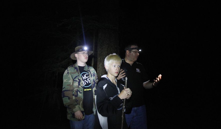 In this July 11, 2014 photo, John Ray, of Marysville, right, and his sons, Mike, 16, left, and Christopher, 12, investigate the forest for signs of bigfoot activity off the Mountain Loop Highway outside of Granite Falls, Wash. Ray and fellow investigator Rob Parker, of Snohomish, work for the Bigfoot Field Researchers Organization checking out areas where bigfoot activity has been reported. (AP Photo/The Herald, Genna Martin)