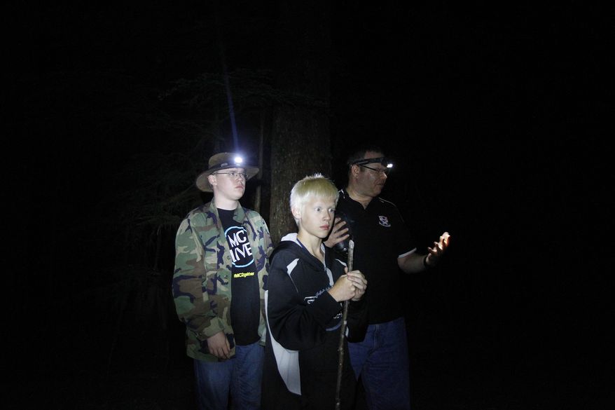 In this July 11, 2014 photo, John Ray, of Marysville, right, and his sons, Mike, 16, left, and Christopher, 12, investigate the forest for signs of bigfoot activity off the Mountain Loop Highway outside of Granite Falls, Wash. Ray and fellow investigator Rob Parker, of Snohomish, work for the Bigfoot Field Researchers Organization checking out areas where bigfoot activity has been reported. (AP Photo/The Herald, Genna Martin)