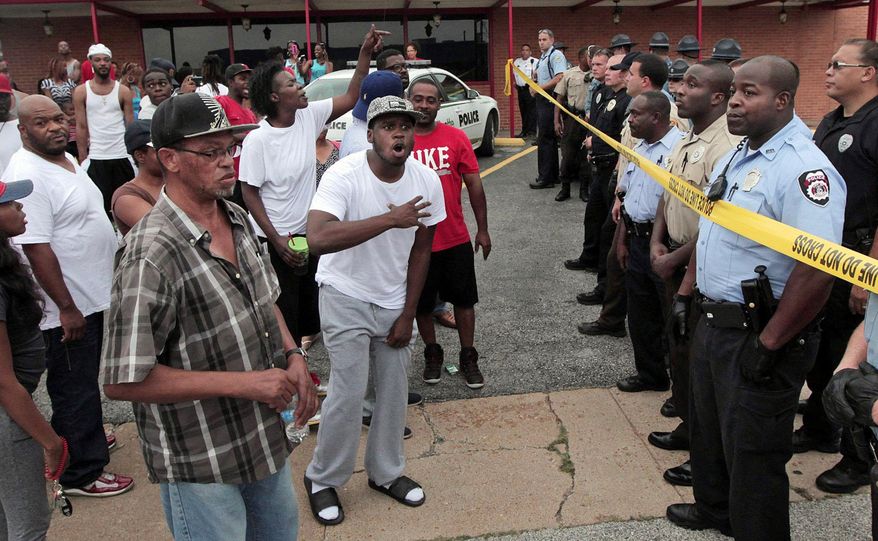 A crowd is stopped by police as they were trying to reach the scene where 18-year-old Michael Brown was fatally shot by police in Ferguson, Mo., near St. Louis on Saturday, Aug. 9, 2014. A spokesman with the St. Louis County Police Department confirmed a Ferguson police officer shot the man. The spokesman didn’t give the reason for the shooting, nor provide the officer’s name or race. (AP Photo/St. Louis Post-Dispatch, Huy Mach)