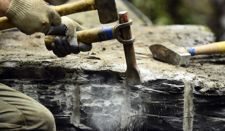 In a Thursday, July 31, 2014 photo, Eric Wood, assistant crew chief with Trails Forever, chisels the edge of a rock before it's used as a walking path on the Chimney Tops Trail in the Great Smoky Mountains National Park near Gatlinburg, Tenn. National Park Service staff and volunteers are reconstructing the popular trail after years of erosion. (AP Photo/Knoxville News Sentinel, Kevin Martin)