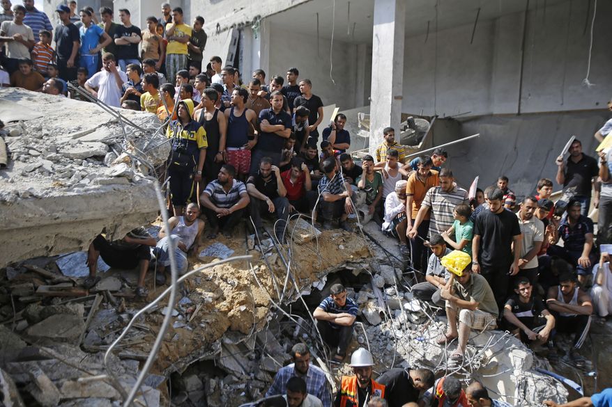 Palestinians gather on the rubble of al-Qassam mosque in Nuseirat refugee camp, central Gaza Strip, after it was hit by an Israeli airstrike, Saturday, Aug. 9, 2014. (AP Photo/Hatem Moussa)