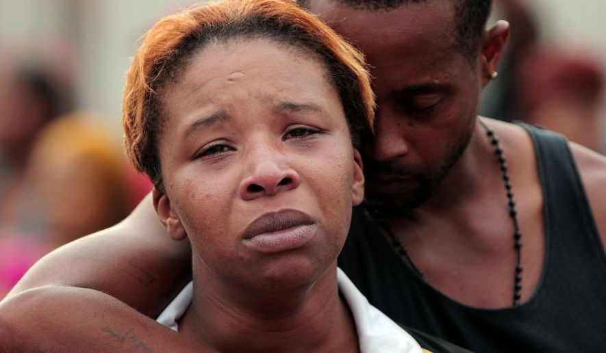 Lesley McSpadden, left, is comforted by her husband, Louis Head, after her 18-year-old son, Michael Brown was shot and killed by police in the middle of the street in Ferguson, Mo., near St. Louis on Saturday, Aug. 9, 2014. A spokesman with the St. Louis County Police Department, which is investigating the shooting at the request of the local department, confirmed a Ferguson police officer shot the man. The spokesman didn't give the reason for the shooting. (AP Photo/St. Louis Post-Dispatch, Huy Mach)