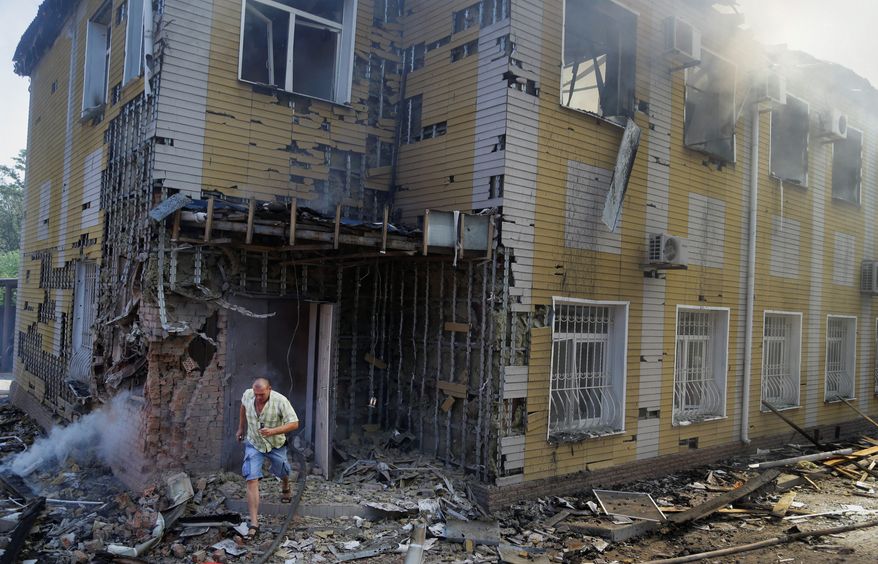 A man runs out of the destroyed building after shelling in Donetsk, eastern Ukraine on Sunday. Fighting raged Sunday in the city despite a request from the pro-Russian rebels there for a cease-fire to prevent a "humanitarian catastrophe." (Associated Press)