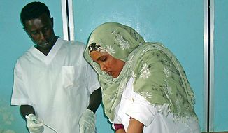 Medical personal in Mogadishu&#x27;s Madina hospital treat a woman wounded by a mortar shell during clashes between Islamist militants and government forces backed by African Union peacekeepers.  (AP Photo/Farah Abdi Warsameh)