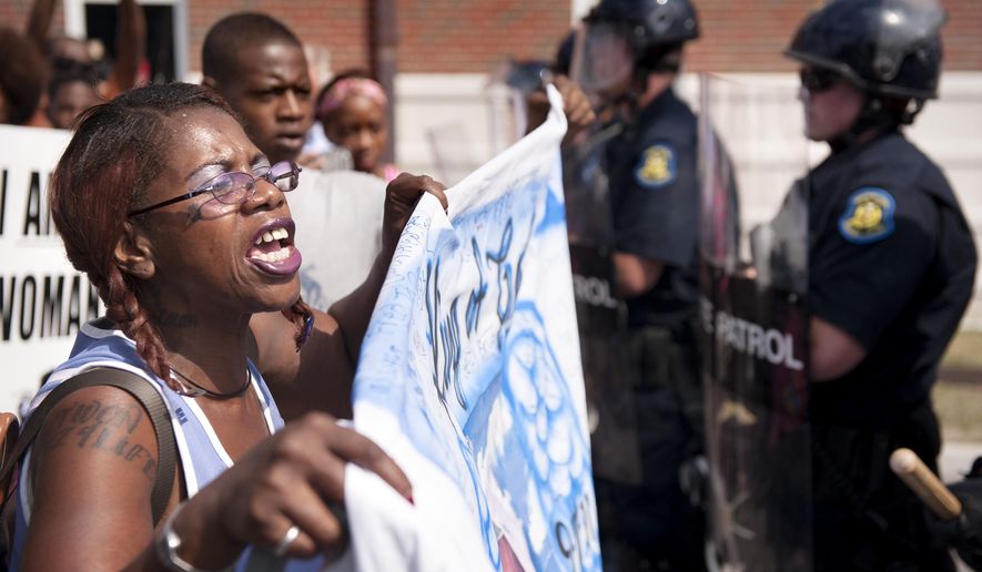 Marcelle Stewart, left, confronts police officers during a march and rally in downtown Ferguson, Mo. Monday, Aug. 11, 2014. The group marched along the closed street, rallying in front of the town's police headquarters to protest the shooting of 18-year-old Michael Brown by Ferguson police officers. Brown, who was killed in a confrontation with police in the St. Louis suburb, was shot Saturday, Aug. 9, 2014, and died following the confrontation with police. Stewart said she was attending the rally because her son-in-law Jason Moore died after being shot with a taser by police. (AP Photo/Sid Hastings)